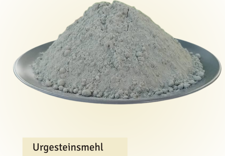 Pile of gray rock flour powder heaped on a silver plate, labeled 'Urgesteinsmehl 500g Packung'